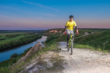 A cyclist cycling along a beautiful mountain path at sunset.