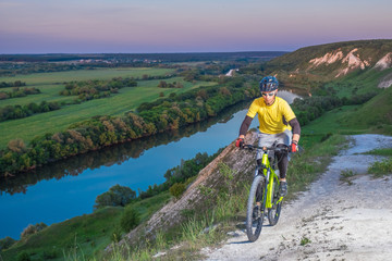 Fototapeta premium A cyclist cycling along a beautiful mountain path at sunset.
