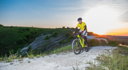 Fototapeta na wymiar A cyclist cycling along a beautiful mountain path at sunset.