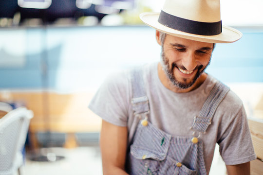 Young Man With Beard and Hat Smiling Outside in Summer
