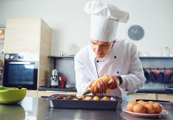 A confectioner in uniform prepares cupcakes in the kitchen.