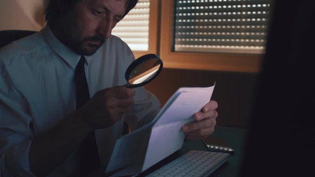 Businessman using magnifying glass to read business contract agreement details in disclaimer in dark office interior