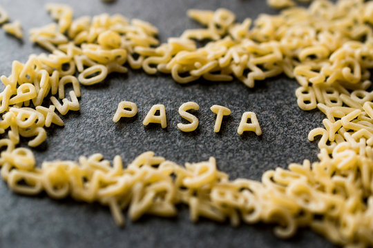 Raw Alphabet Pasta is Written with Letters  on Granit Grey Surface.
