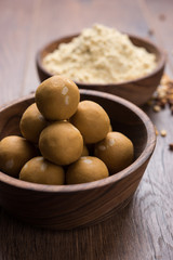 Chick pea flour or Besan powder in a ceramic or wooden bowl along with sweet Laddu or laddoo
