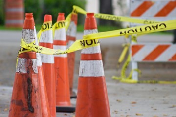 Orange traffic cones with yellow caution tape, shallow focus and intentional blurr
