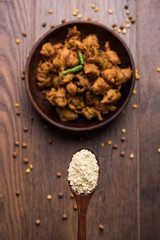 Chick pea flour or Besan powder in a ceramic or wooden bowl along with fried onion pakora or kanda bajji