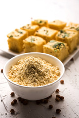 Chick pea flour or Besan powder in a ceramic or wooden bowl along with Gujrati Dhokla snack