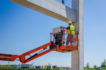 Worker is helping crane from cherry picker, keep balance and direction