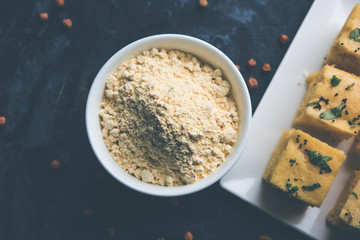 Chick pea flour or Besan powder in a ceramic or wooden bowl along with Gujrati Dhokla snack
