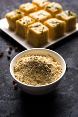 Chick pea flour or Besan powder in a ceramic or wooden bowl along with Gujrati Dhokla snack