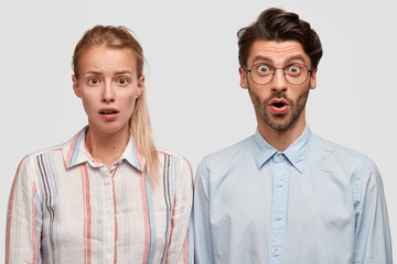 Portrait of stunned female and male colleagues have stupefied expressions, look with bated breath, being not ready to prepare deadline task, isolated over white background. People, cooperation concept
