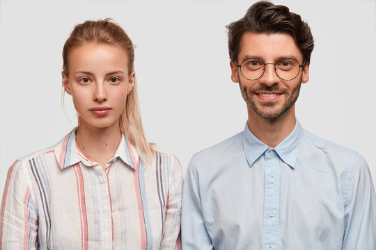 Horizontal shot of beautiful young female in formal shirt, has hair tied in pony tail, spends free time with her lover who has pleased expression. People, love, relationship and lifestyle concept