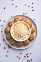 Chick pea flour or Besan powder in a ceramic or wooden bowl along with sweet Laddu or laddoo