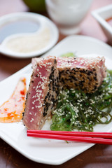 Close-up of roasted slices of tuna fillet with chuka salad, selective focus, vertical shot