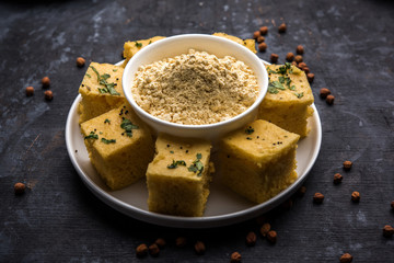 Chick pea flour or Besan powder in a ceramic or wooden bowl along with Gujrati Dhokla snack