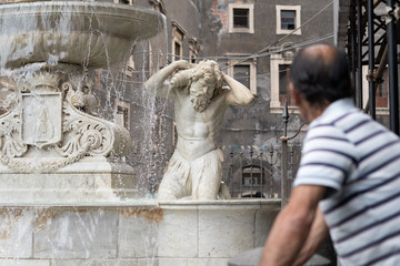 Catania, people standing outoor in front of the Amenano Fountain in the Dome square