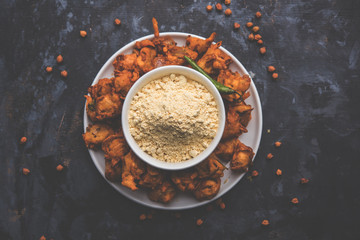 Chick pea flour or Besan powder in a ceramic or wooden bowl along with fried onion pakora or kanda bajji