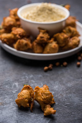 Chick pea flour or Besan powder in a ceramic or wooden bowl along with fried onion pakora or kanda bajji