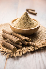 Ayurvedic Mulethi or Liquorice root stick or jeshthamadh powder served in a bowl over moody...