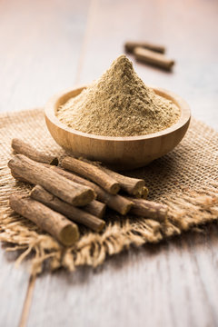 Ayurvedic Mulethi or Liquorice root stick or jeshthamadh powder served in a bowl over moody background