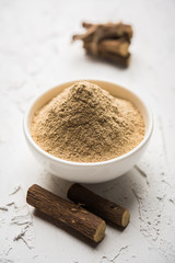 Ayurvedic Mulethi or Liquorice root stick or jeshthamadh powder served in a bowl over moody background