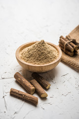 Ayurvedic Mulethi or Liquorice root stick or jeshthamadh powder served in a bowl over moody background
