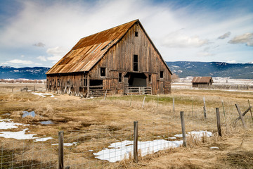 Farmers barn in rural Idaho with fence and some snow on the ground
