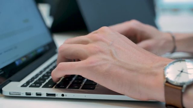 Guy writing and working on a laptop