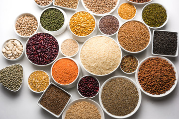 Uncooked pulses,grains and seeds in White bowls over white background. selective focus