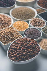 Uncooked pulses,grains and seeds in White bowls over white background. selective focus