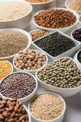 Uncooked pulses,grains and seeds in White bowls over white background. selective focus