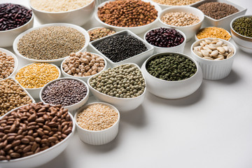 Uncooked pulses,grains and seeds in White bowls over white background. selective focus