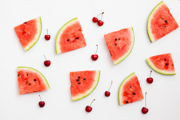 Pieces of watermelon and cherries on a white background