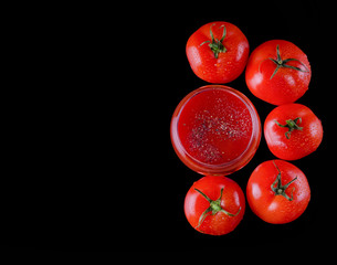 red, juicy, fresh tomatoes and tomato juice on a black background