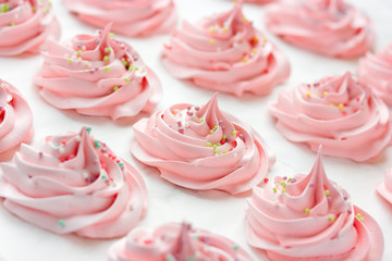 Homemade marshmallow, fluffy dessert zephyr, pink swirl meringue with colorful sugar sprinkles close up