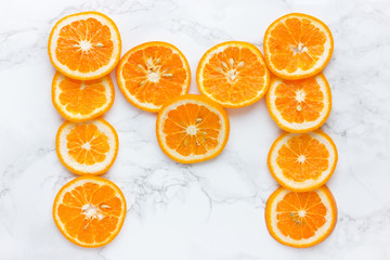 Mandarin slices letter m on white background