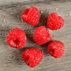 Top view photo of six red raspberries on gray wooden table.