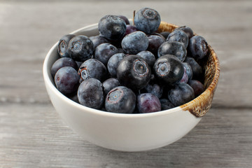Close up on small white porcelain bowl full of blueberries.