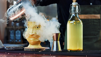 The bartender pours steam in a Tiki glass