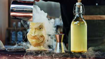 The bartender pours steam in a Tiki glass