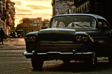 Old classic car in a street of havana, cuba with sunset on background