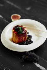 Delicious cake served with blueberries, jam and mint leaves on round plate, fig and cornflowers lying on blue aged wooden surface. Tasty gourmet berry dessert, appetizing sweet meal. Top view.