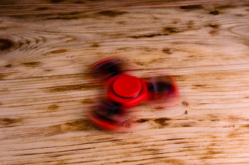 Red fidget spinner rotates on wooden desk