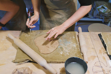 Making dirty hands of raw clay ware in a pottery workshop