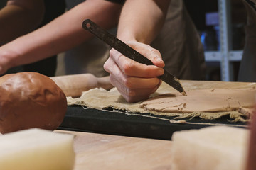Making dirty hands of raw clay ware in a pottery workshop