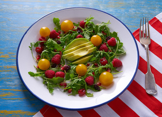 Avocado and berries salad with arugula and tomato