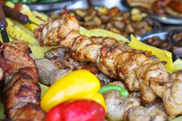 Fried meat of pig, lamb, grilled shish kebab with a delicious crust on the background of vegetables. Summer holidays and food in nature. Stock Photo.