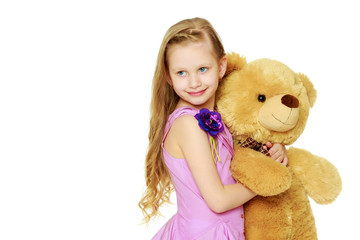Beautiful little girl 5-6 years.She is holding a large teddy bea