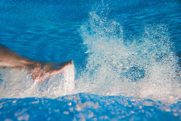 Men's legs swimming underwater in the swimming pool in summer