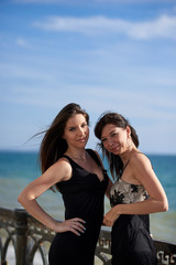 two young woman in a black dresses near the sea